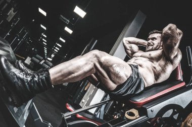 Beyaz kas yakışıklı modeli görünüm egzersiz jimnastik salonu Eğitim kuadriseps bacaklar ve makineleri ve pompalama bir halter ile hamstrings ve fitness vücut geliştirme ve spor beslenme pozlar