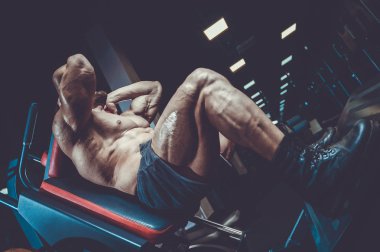 Beyaz kas yakışıklı modeli görünüm egzersiz jimnastik salonu Eğitim kuadriseps bacaklar ve makineleri ve pompalama bir halter ile hamstrings ve fitness vücut geliştirme ve spor beslenme pozlar