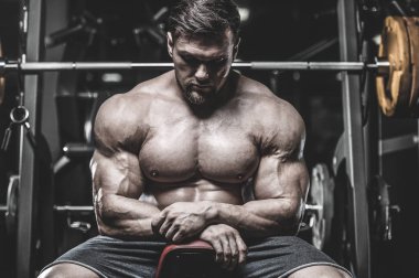 Vahşi seksi vücut geliştirme sporcusu kaslarını çalıştıran vücut geliştirme konsepti geliştiren sporcu. Spor salonunda çıplak vücut geliştirme egzersizleri yapan kaslı yakışıklı erkekler.