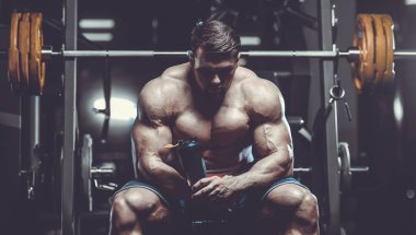 Vahşi seksi vücut geliştirme sporcusu kaslarını çalıştıran vücut geliştirme konsepti geliştiren sporcu. Spor salonunda çıplak vücut geliştirme egzersizleri yapan kaslı yakışıklı erkekler.