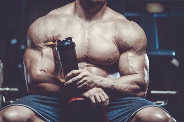 Vahşi seksi vücut geliştirme sporcusu kaslarını çalıştıran vücut geliştirme konsepti geliştiren sporcu. Spor salonunda çıplak vücut geliştirme egzersizleri yapan kaslı yakışıklı erkekler.