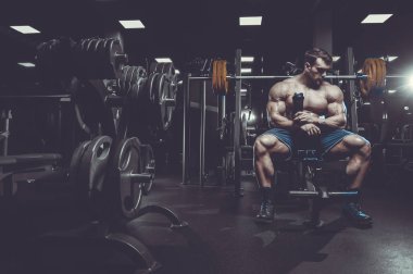 Vahşi seksi vücut geliştirme sporcusu kaslarını çalıştıran vücut geliştirme konsepti geliştiren sporcu. Spor salonunda çıplak vücut geliştirme egzersizleri yapan kaslı yakışıklı erkekler.