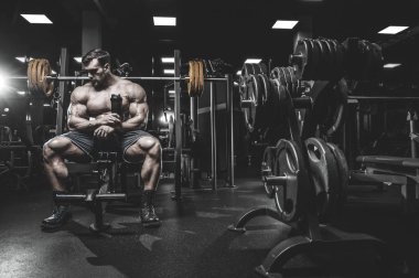 Vahşi seksi vücut geliştirme sporcusu kaslarını çalıştıran vücut geliştirme konsepti geliştiren sporcu. Spor salonunda çıplak vücut geliştirme egzersizleri yapan kaslı yakışıklı erkekler.