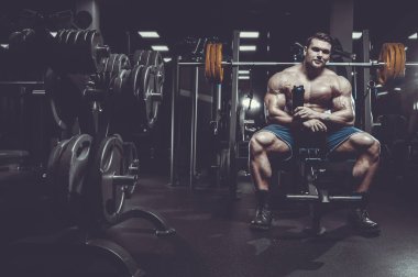 Vahşi seksi vücut geliştirme sporcusu kaslarını çalıştıran vücut geliştirme konsepti geliştiren sporcu. Spor salonunda çıplak vücut geliştirme egzersizleri yapan kaslı yakışıklı erkekler.