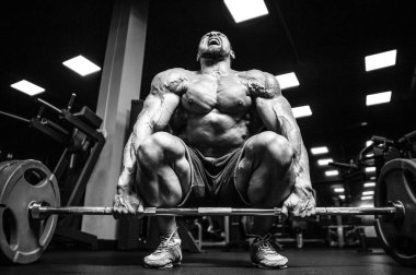 Beyaz kas yakışıklı modeli görünüm egzersiz jimnastik salonu Eğitim kuadriseps bacaklar ve makineleri ve pompalama bir halter ile hamstrings ve fitness vücut geliştirme ve spor beslenme pozlar