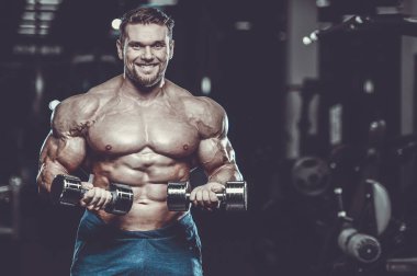 Vahşi seksi vücut geliştirme sporcusu kaslarını çalıştıran vücut geliştirme konsepti geliştiren sporcu. Spor salonunda çıplak vücut geliştirme egzersizleri yapan kaslı yakışıklı erkekler.