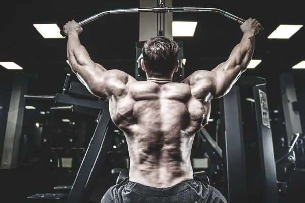 英俊残暴的白种人强壮的年轻肌肉男子模型外观锻炼训练在健身健美和运动营养中抽回肌肉的拉图 — 图库照片