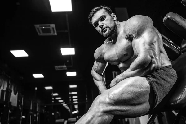 Beyaz kas yakışıklı modeli görünüm egzersiz jimnastik salonu Eğitim kuadriseps bacaklar ve makineleri ve pompalama bir halter ile hamstrings ve fitness vücut geliştirme ve spor beslenme pozlar