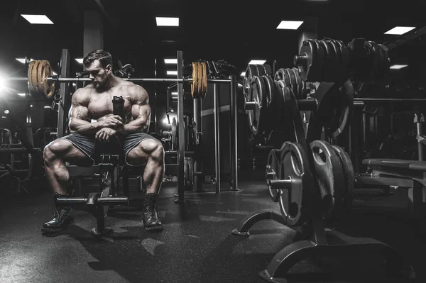 Vahşi seksi vücut geliştirme sporcusu kaslarını çalıştıran vücut geliştirme konsepti geliştiren sporcu. Spor salonunda çıplak vücut geliştirme egzersizleri yapan kaslı yakışıklı erkekler.