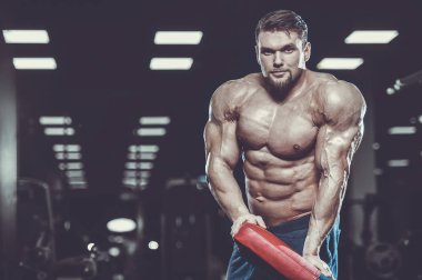 Vahşi seksi vücut geliştirme sporcusu kaslarını çalıştıran vücut geliştirme konsepti geliştiren sporcu. Spor salonunda çıplak vücut geliştirme egzersizleri yapan kaslı yakışıklı erkekler.