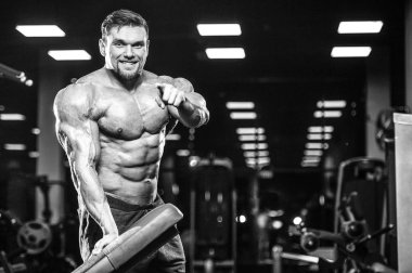 Vahşi seksi vücut geliştirme sporcusu kaslarını çalıştıran vücut geliştirme konsepti geliştiren sporcu. Spor salonunda çıplak vücut geliştirme egzersizleri yapan kaslı yakışıklı erkekler.