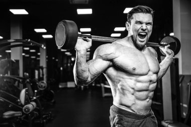 Beyaz kas yakışıklı modeli görünüm egzersiz jimnastik salonu Eğitim kuadriseps bacaklar ve makineleri ve pompalama bir halter ile hamstrings ve fitness vücut geliştirme ve spor beslenme pozlar