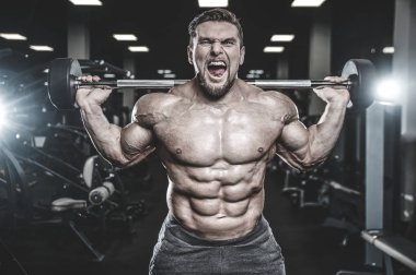Beyaz kas yakışıklı modeli görünüm egzersiz jimnastik salonu Eğitim kuadriseps bacaklar ve makineleri ve pompalama bir halter ile hamstrings ve fitness vücut geliştirme ve spor beslenme pozlar