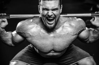 Beyaz kas yakışıklı modeli görünüm egzersiz jimnastik salonu Eğitim kuadriseps bacaklar ve makineleri ve pompalama bir halter ile hamstrings ve fitness vücut geliştirme ve spor beslenme pozlar