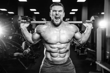 Beyaz kas yakışıklı modeli görünüm egzersiz jimnastik salonu Eğitim kuadriseps bacaklar ve makineleri ve pompalama bir halter ile hamstrings ve fitness vücut geliştirme ve spor beslenme pozlar