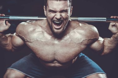 Vahşi seksi vücut geliştirme sporcusu kaslarını çalıştıran vücut geliştirme konsepti geliştiren sporcu. Spor salonunda çıplak vücut geliştirme egzersizleri yapan kaslı yakışıklı erkekler.