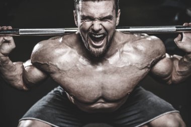 Beyaz kas yakışıklı modeli görünüm egzersiz jimnastik salonu Eğitim kuadriseps bacaklar ve makineleri ve pompalama bir halter ile hamstrings ve fitness vücut geliştirme ve spor beslenme pozlar