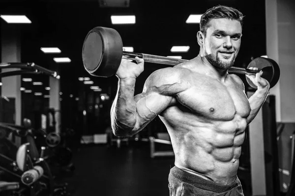 英俊的白种人肌肉男子模型在健身房训练腿部四头肌和腿筋在机器上 并与杠铃抽水 并构成健身健美和运动营养 — 图库照片