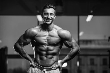 Yakışıklı, formda, kaslı, beyaz bir adam spor salonunda antrenman yapıyor. Kilo alıyor, kaslarını şişiriyor, fitness ve vücut geliştirme sporları yapıyor.