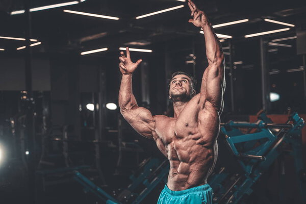 Handsome young fit muscular caucasian man of model appearance workout training in the gym gaining weight pumping up muscle, poses, drinks water  fitness and bodybuilding sport nutrition concept