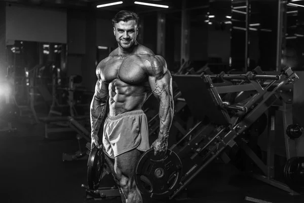 Handsome young fit muscular caucasian man of model appearance workout training in the gym gaining weight pumping up muscle, poses, drinks water  fitness and bodybuilding sport nutrition concept