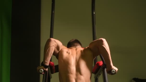 英俊的运动男子在高低杠锻炼健身练习和健美概念背景上肌肉俯卧撑 肌肉发达的健美健身男子在健身房做酒吧运动赤裸躯干4K — 图库视频影像