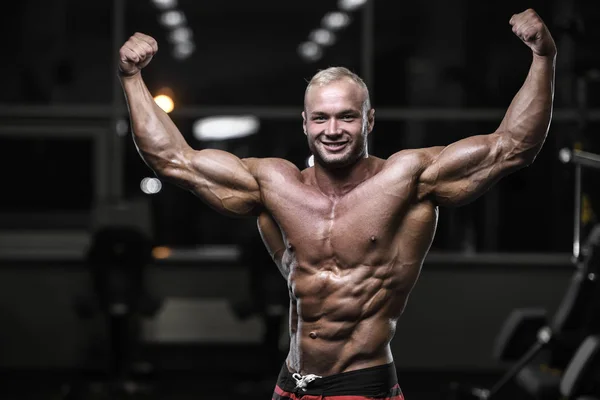 Handsome strong bodybuilder athletic men pumping up muscles with — Stock Photo, Image