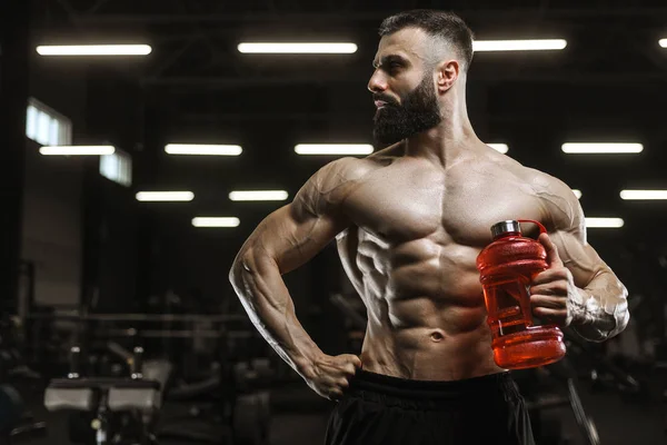 Красивые сильные спортивные мышцы мужчины пьют воду и спортивные нутри — стоковое фото