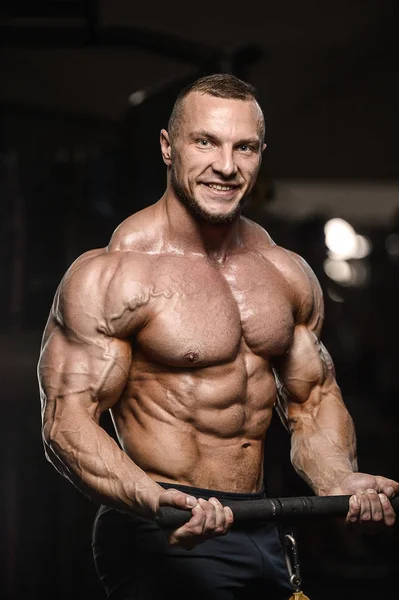 Musculoso fisiculturista homens fitness fazendo exercícios de armas no ginásio — Fotografia de Stock