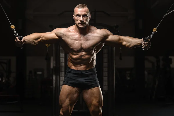 Muskularny kulturysta fitness mężczyzn robi ćwiczenia broni w siłowni — Zdjęcie stockowe