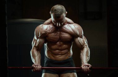 Vücut geliştirici kasları şişiriyor vücut geliştirme egzersizi yapıyor ve sağlıklı bir konsept geliştiriyor. Vücut geliştiren adamlar spor salonunda çıplak vücut egzersizleri yapıyor. Yakışıklı, güçlü, atletik sert adam.