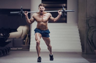 Adam bacak kaslarını şişiriyor vücut geliştirme konsepti tasarlıyor spor salonu arka plan egzersizleri spor salonunda çıplak gövde.