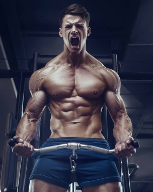 Vücut geliştirici yakışıklı güçlü atletik sert adam kaslarını şişiriyor kaslarını çalıştırıyor vücut geliştiriyor sağlıklı bir konsept geliştiriyor kaslı fitness adamları spor salonunda çıplak bedende kol egzersizleri yapıyor.