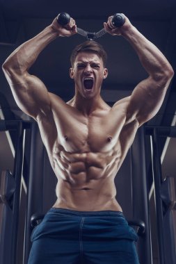 Vücut geliştirici yakışıklı güçlü atletik sert adam triceps kaslarını şişiriyor vücut geliştirme konsepti sağlıklı tasarım - kaslı fitness erkekler spor salonunda çıplak gövde egzersizleri yapıyor