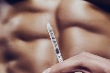 Vücut geliştirici spor salonunda steroid enjeksiyonu yapıyor. Güçlü atletik kaba kaslı adam karın kaslarını çalıştırıyor spor yapıyor ve sağlıklı konsept tasarımı yapıyor. Karın egzersizleri çıplak gövde