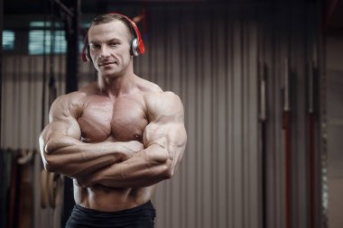Spor salonunda kulaklığı olan fitness adamı. Vücut geliştirme konsepti, kas geliştirme, vücut geliştirme, vücut geliştirme, vücut geliştirme, vücut geliştirme, vücut geliştirme. İyi görünümlü güçlü atletik sert adam egzersizi.
