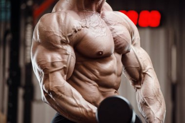 Vücut geliştirici kasları şişiriyor vücut geliştirme egzersizi yapıyor ve sağlıklı bir konsept geliştiriyor. Vücut geliştiren adamlar spor salonunda çıplak vücut egzersizleri yapıyor. Yakışıklı, güçlü, atletik sert adam.