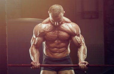 Vücut geliştirici kasları şişiriyor vücut geliştirme egzersizi yapıyor ve sağlıklı bir konsept geliştiriyor. Vücut geliştiren adamlar spor salonunda çıplak vücut egzersizleri yapıyor. Yakışıklı, güçlü, atletik sert adam.