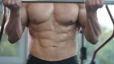 Beyaz tenli atletik adam kaslarını şişiriyor. Güçlü vücut geliştirici, karın kasları, trisepsleri, göğsü ve omuzları var. Fitness ve vücut geliştirme konsepti