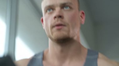 Spor giyimli beyaz bir genç spor salonunda koşu bandında koşuyor. Fitness, vücut geliştirme ve yağ yakma konsepti 