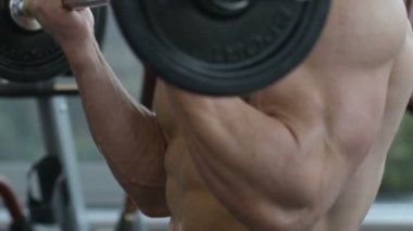 Beyaz tenli atletik adam kaslarını şişiriyor. Güçlü vücut geliştirici, karın kasları, trisepsleri, göğsü ve omuzları var. Fitness ve vücut geliştirme konsepti