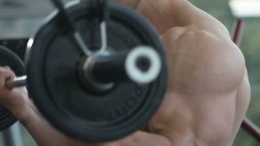 Beyaz tenli atletik adam kaslarını şişiriyor. Güçlü vücut geliştirici, karın kasları, trisepsleri, göğsü ve omuzları var. Fitness ve vücut geliştirme konsepti