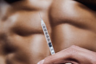 Vücut geliştirici spor salonunda steroid enjeksiyonu yapıyor. Güçlü atletik kaba kaslı adam karın kaslarını çalıştırıyor spor yapıyor ve sağlıklı konsept tasarımı yapıyor. Karın egzersizleri çıplak gövde
