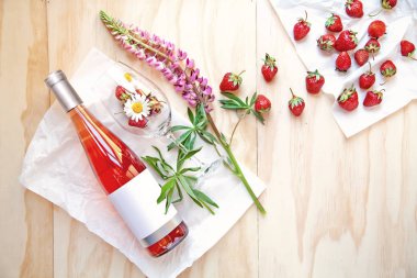 Bir şişe beyaz şarap ve çilek ve çiçekler ile cam