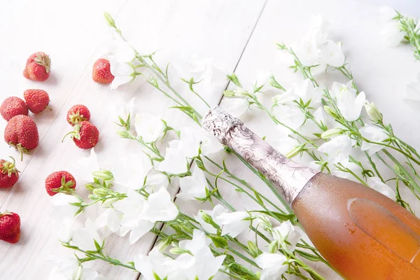 beyaz çiçekler ve çilek ile ahşap bir arka plan üzerinde pembe şampanya