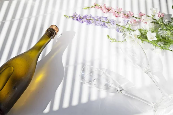 soğuk şampanya çiçek bardak güneşlikler aracılığıyla ışık beyaz bir arka plan üzerinde yatıyor