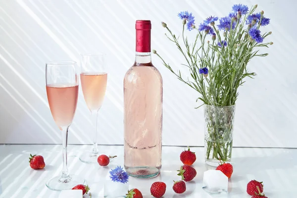 gözlük ve çilek ile beyaz bir arka planda gül şarabı şişe