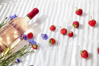 yaz güneşi ışığında parlak bir arka plan üzerinde gül şarap şişesi Çilek Mavi cornflowers