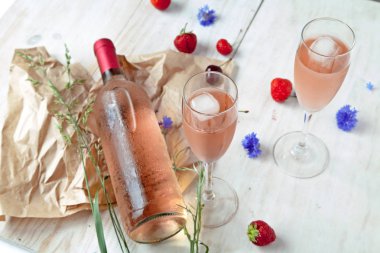 Beyaz ahşap masa üzerinde rustik tahta üzerinde pembe şarap ve şarap bardakları şişe. Şarap tadımı konsepti