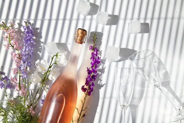 Vino espumoso rosa, vasos y flores están acostados en la mesa —  Fotos de Stock